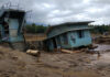 A collapsed building and debris in a muddy area after a flood