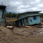 A collapsed building and debris in a muddy area after a flood