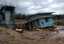 A collapsed building and debris in a muddy area after a flood
