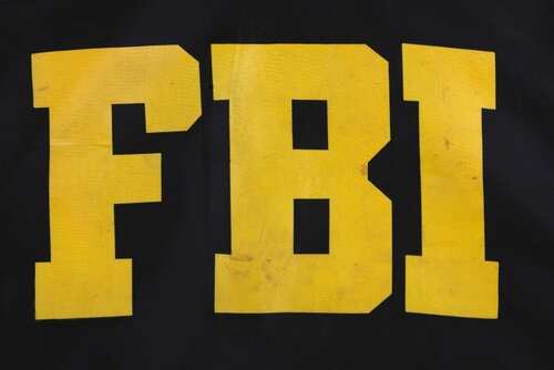 shutterstock_2220332053.jpg Close-up of the letters 'FBI' in yellow on a black background
