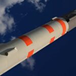 A missile with orange and gray markings against a blue sky
