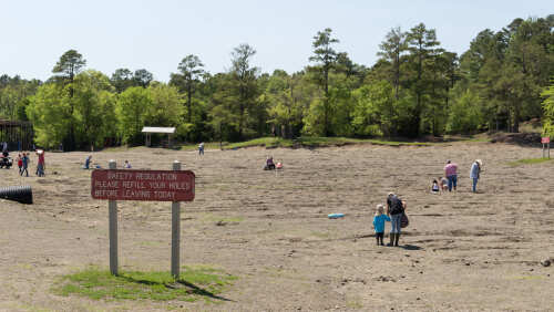 shutterstock_1089849938.jpg Families enjoying outdoor activities in a recreational area with a safety sign