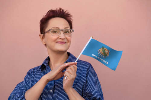 Woman holding an Oklahoma flag and smiling