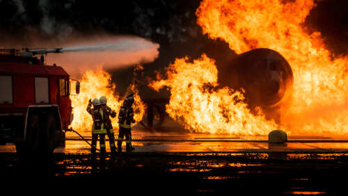 shutterstock_1482571625.jpg Firefighters battling a large blaze with a fire truck in the foreground