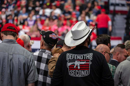 Crowd of supporters at a political rally, some wearing hats and shirts with slogans