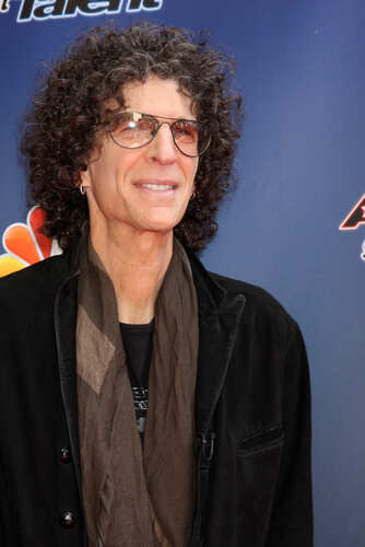 shutterstock_188729087.jpg A man with curly hair and glasses smiling at a red carpet event