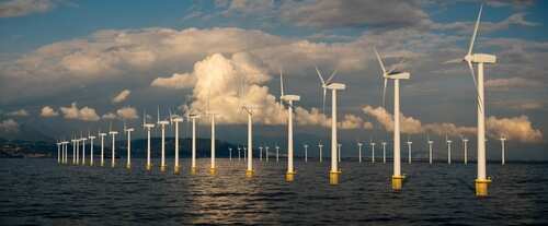 Offshore wind turbines in a body of water under a cloudy sky