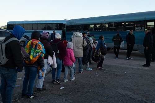 A line of people waiting to board a bus at a station