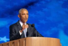 A man in a suit delivering a speech at a podium