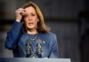 Female politician speaking at a podium with microphones