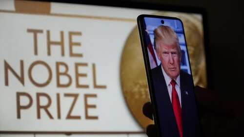 A mobile phone displaying a political figure in front of a screen showing 'The Nobel Prize'