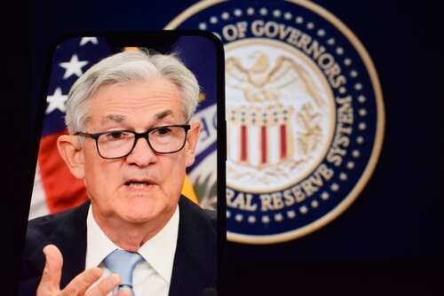 A man speaking during a press conference with the Federal Reserve emblem in the background