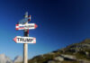 A directional signpost with arrows pointing to 'RUSSIA' and 'TRUMP' against a clear blue sky