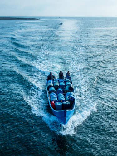 A fishing boat with three people navigating through the ocean