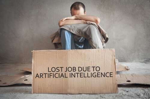 shutterstock_2269843473.jpg A person sitting on the floor with their head down, next to a cardboard sign about job loss due to AI