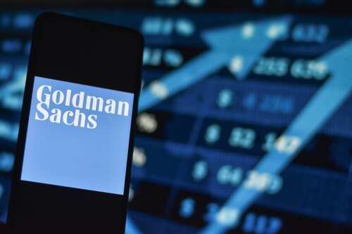 Mobile phone displaying Goldman Sachs logo in front of stock market data