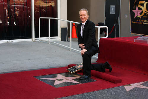 A man kneeling beside a star on the Hollywood Walk of Fame