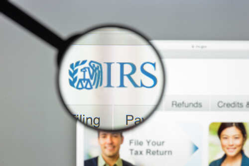 Close-up view of the IRS logo on a website through a magnifying glass