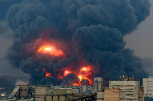 Large industrial fire with thick black smoke and flames