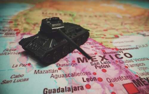 shutterstock_2145720143.jpg A toy tank placed on a map highlighting Mexico