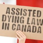 Organ Harvesting Shocker: Canada’s Dark Secret? A hand holding a cardboard sign that reads 'Assisted Dying Law in Canada' with a blurred Canadian flag in the background