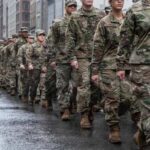 A line of soldiers in military uniforms marching down a city street