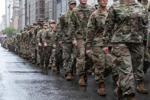 A line of soldiers in military uniforms marching down a city street