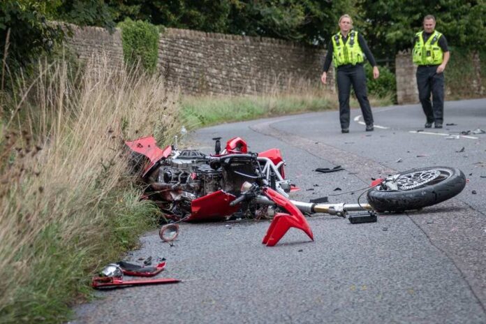 shutterstock_2284630619 (1).jpg A damaged motorcycle on the side of the road with police officers nearby
