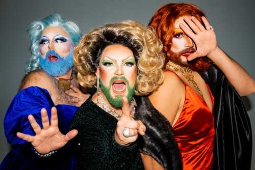 Three drag performers posing dramatically in vibrant costumes and makeup