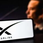 Starlink Fuels Fraud Boom—Unbelievable! A smartphone displaying the Starlink logo with a blurred figure in the background