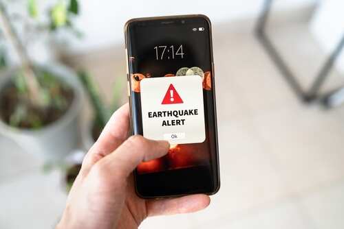 shutterstock_2489978335.jpg A hand holding a smartphone displaying an earthquake alert notification