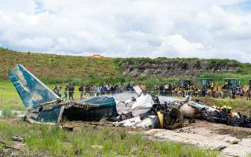 Wreckage of a crashed airplane with emergency responders and onlookers
