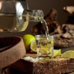 Tequila and Flames — Newsom’s Scandalous Night A shot glass being filled with tequila next to lime slices and salt