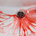 Red liquid splattered around a sink drain