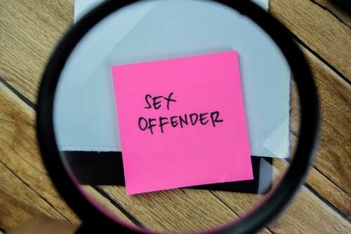 A magnifying glass focusing on a pink sticky note that reads 'SEX OFFENDER'