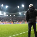 Soccer coach observing the game from the sidelines at night
