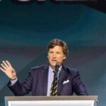 A man in a suit speaking at a podium during a conference
