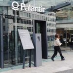 Entrance of a Palantir office building with a woman walking by