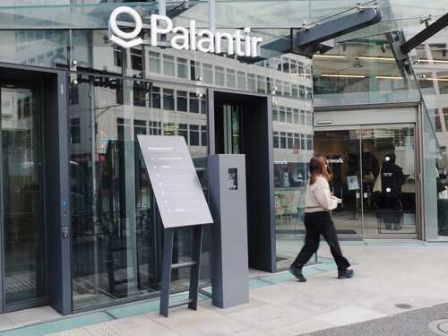 Entrance of a Palantir office building with a woman walking by