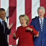 Three public figures smiling and engaging with an audience at a political event