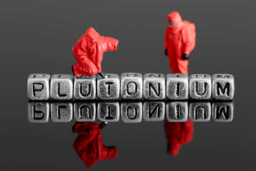 Miniature figures in protective suits next to the word 'PLUTONIUM' made of metal letters