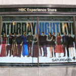 Promotional display for Saturday Night Live featuring the cast in various outfits