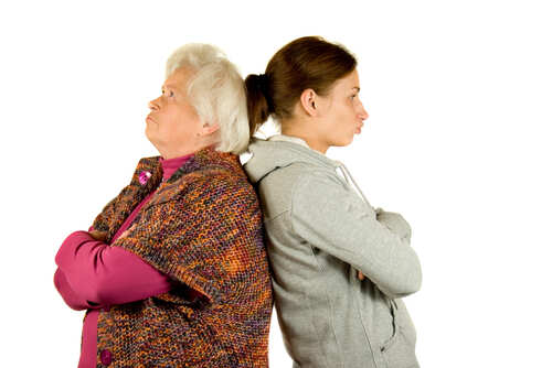 An older woman and a younger woman standing back to back with displeased expressions