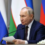 Man speaking at conference with flags in background