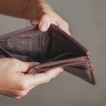 A person holding an empty brown leather wallet