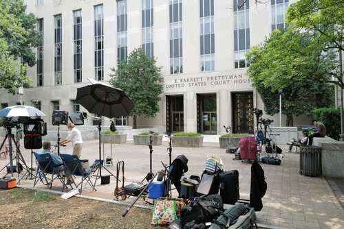Media equipment and journalists outside a courthouse