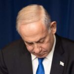 A political figure in formal attire looking down