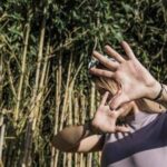 A person with raised hands in front of a bamboo backdrop