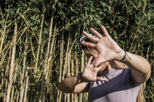 A person with raised hands in front of a bamboo backdrop