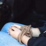 Hands bound with rope resting on a lap